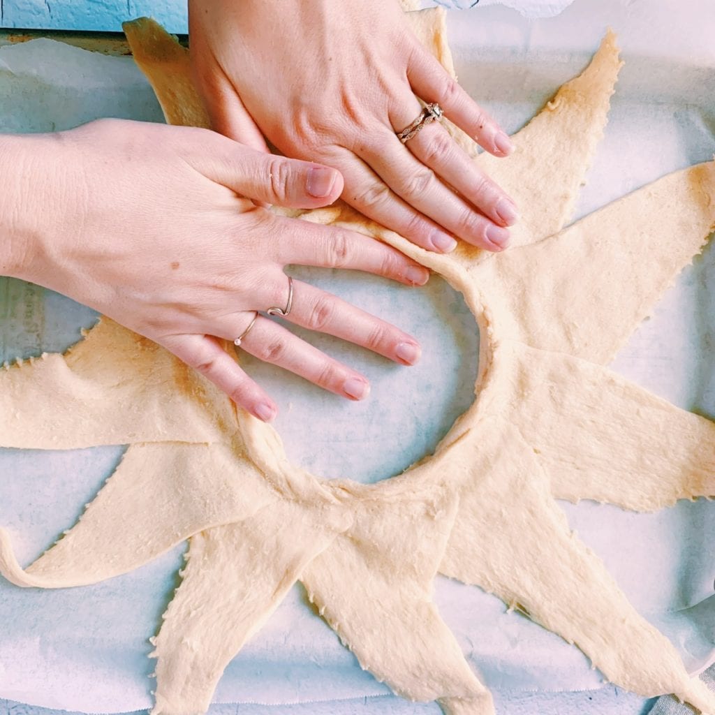 Hands pressing around the center of a crescent ring circle to create a lip to keep filling in.
