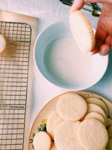 Shortbread cookie being dipped in lemon glaze