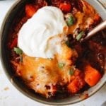 Close up of thick and heart sweet potato black bean chili topped with sour cream and cilantro
