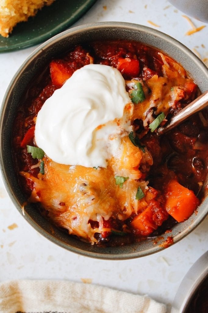 Close up of thick and heart sweet potato black bean chili topped with sour cream and cilantro