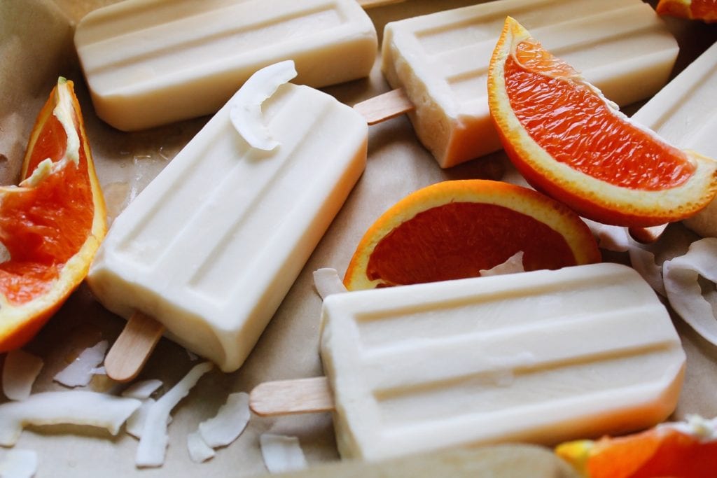 orange coconut milk popsicles with orange slices and coconut shreds