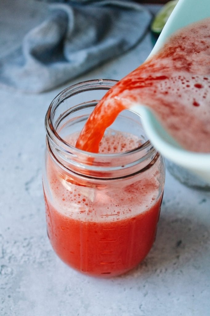 watermelon liquid being poured into a jar