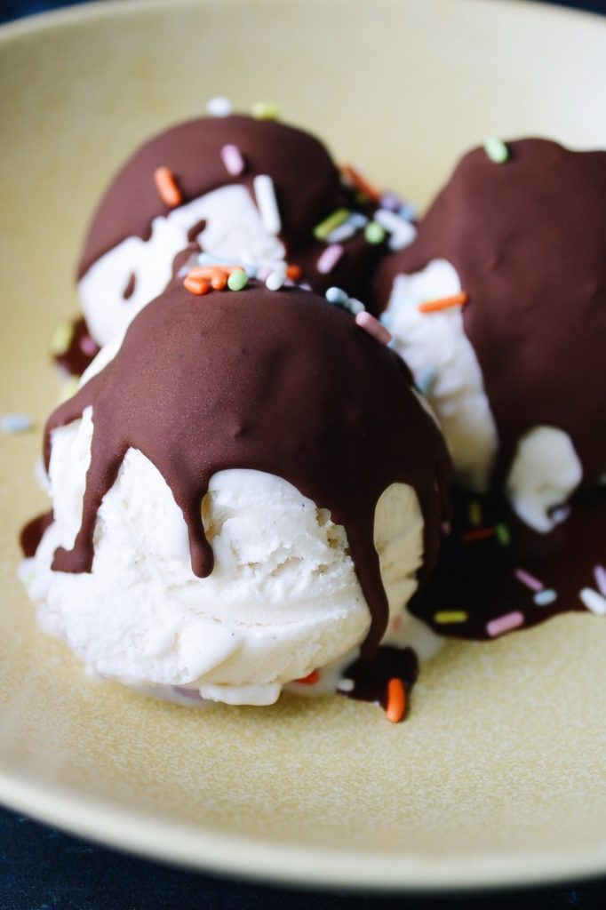 close up of vanilla ice cream scoops with chocolate shell ice cream topping
