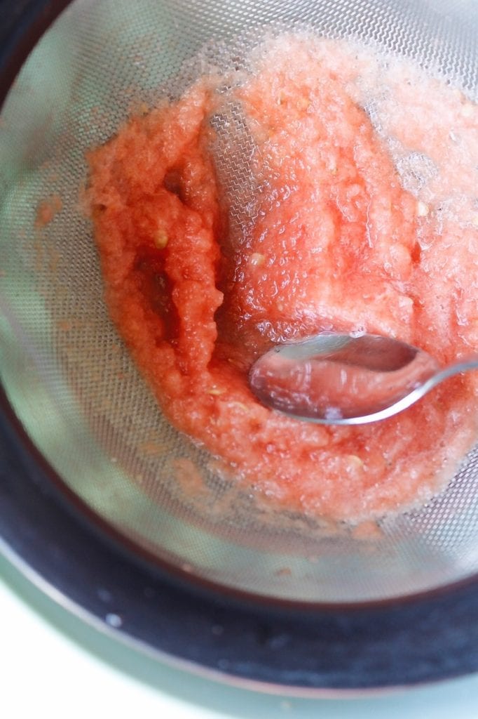 watermelon liquid being put through a strainer