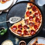 Sourdough discard pizza on a cast iron skillet with pepperoni and black olives