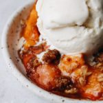 rhubarb and nectarine crumble with ice cream on a speckled plate
