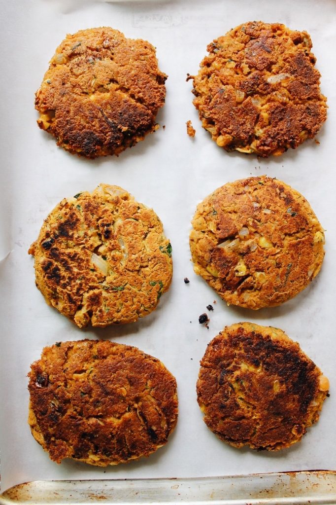 cooked chickpea burgers on a parchment lined baking sheet