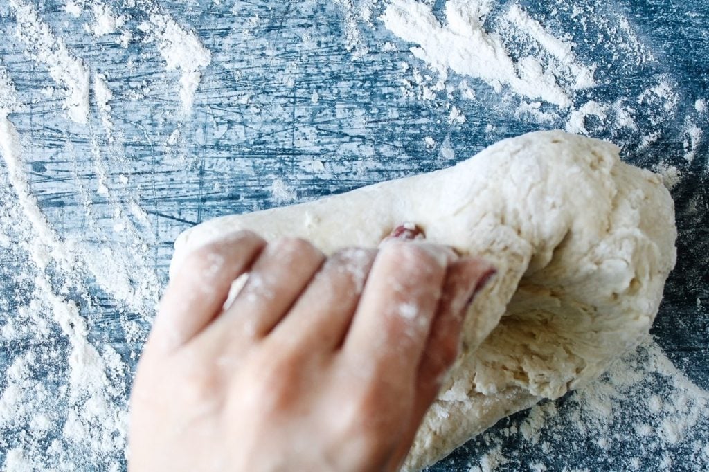 pizza dough being kneaded by hand