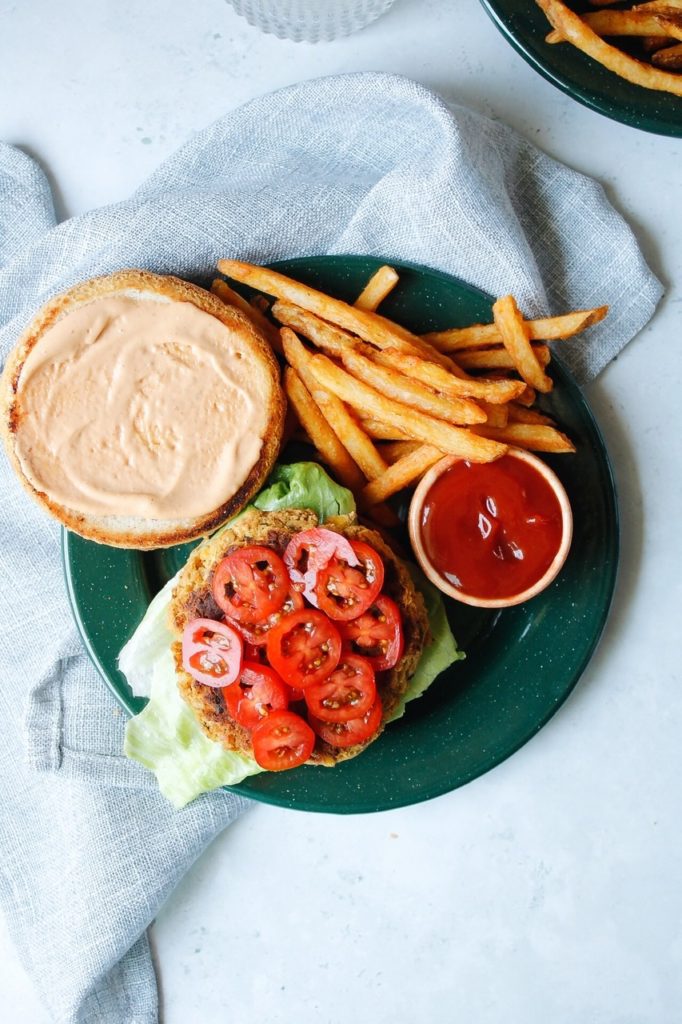 open faced chickpea burger on a green plate with french fries