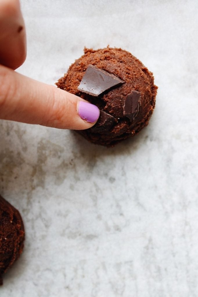 chocolate chunks being pressed into a dropped ball of cookie dough