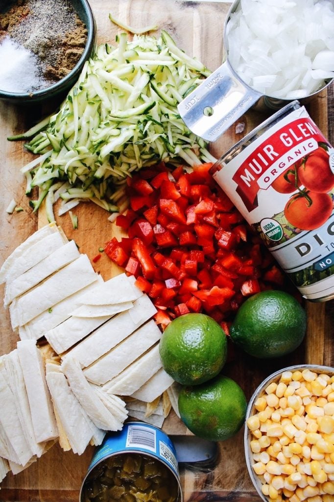 ingredients for healthy chicken tortilla soup laid out on a cutting board