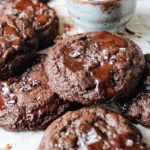Double chocolate cookies stacked on a baking sheet with parchment paper