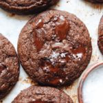 double chocolate cookies on a baking sheet with a small bowl of sea salt