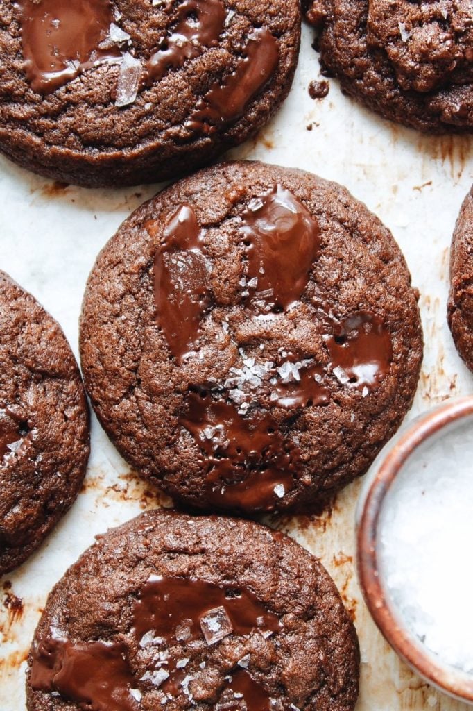 double chocolate cookies on a baking sheet with a small bowl of sea salt