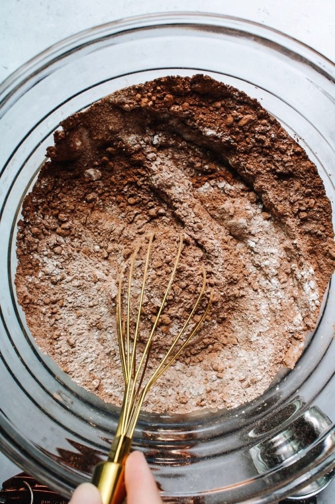 dry ingredients for sourdough chocolate cake being whisked in a glass bowl