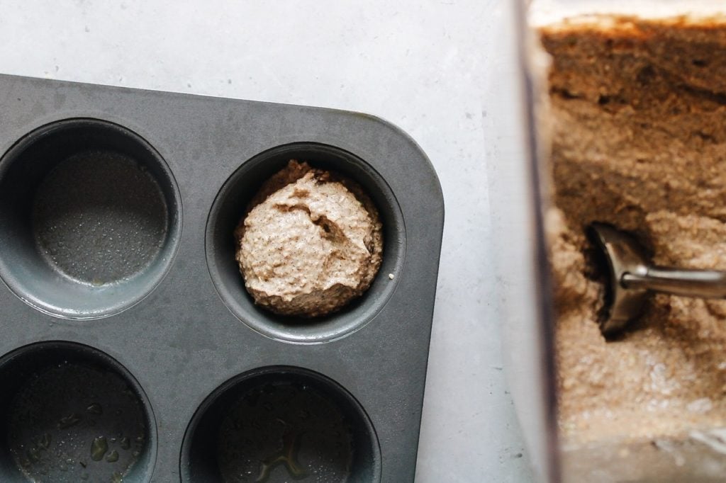 muffin batter being scooped into a muffin tin