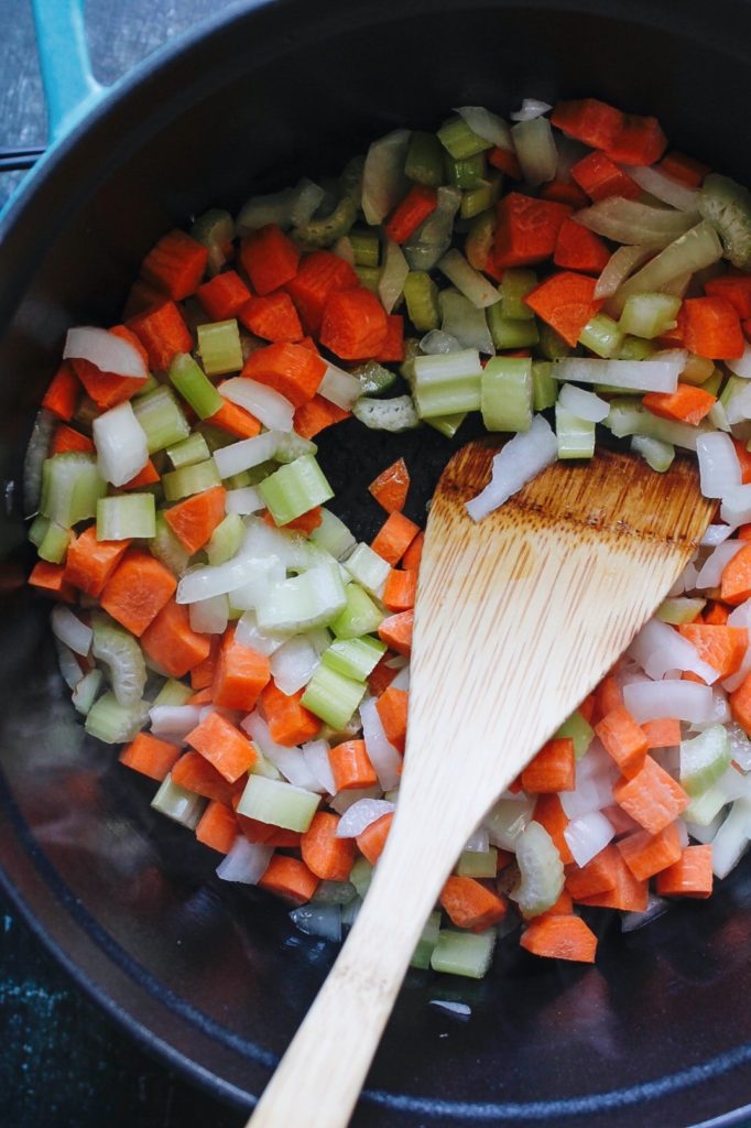 celery, carrot and onion being cooked in a dutch oven until softened
