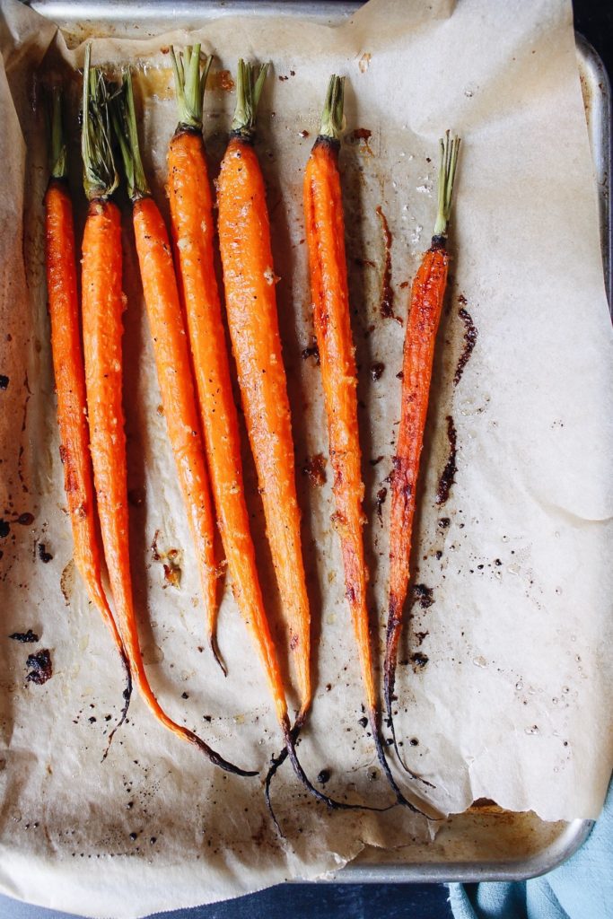 roasted carrots with honey, ginger and garlic on a baking sheet. 