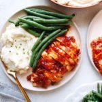 plated baked saucy chicken with mashed potatoes and green beans