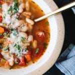 vegetable bean soup in a beige bowl with a gold spoon