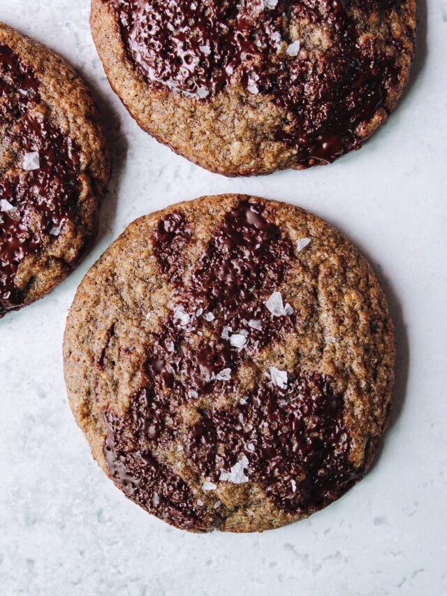 buckwheat chocolate chip cookies topped with sea salt on a white background