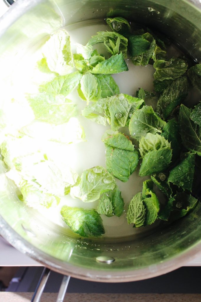 mint leaves, water and sugar in a pot on the stove to make peppermint simple syrup