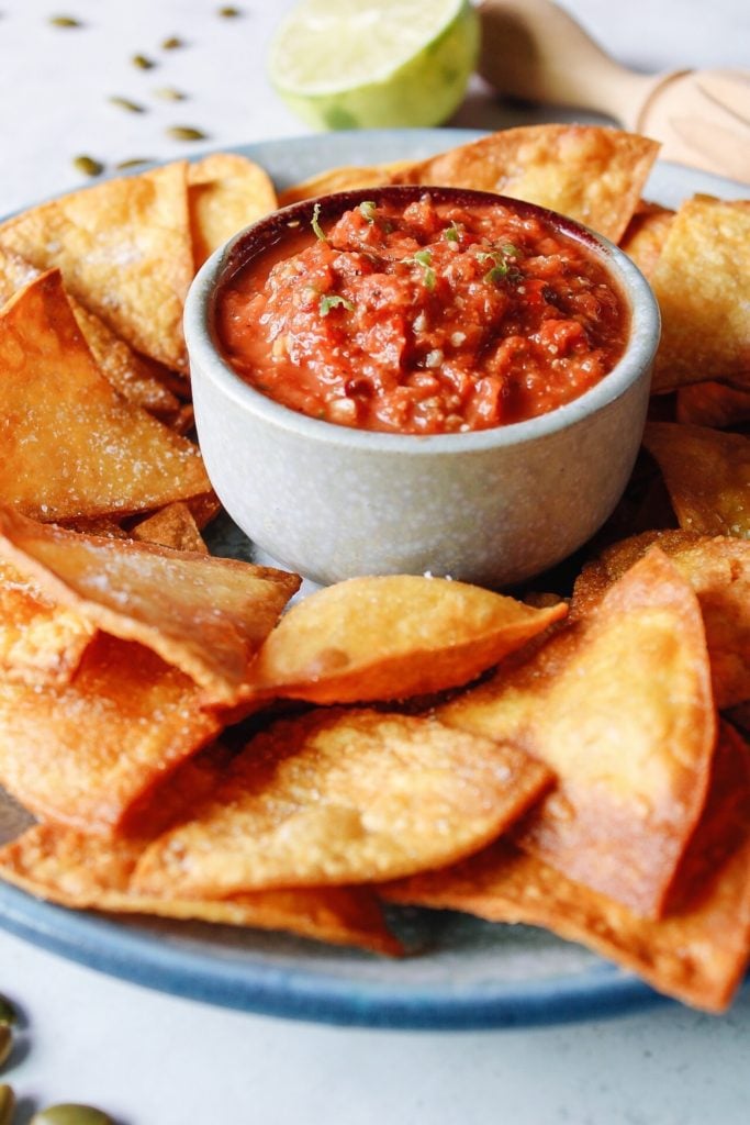 roasted pepita salsa in a chips and dip bowl surrounded by homemade tortilla chips