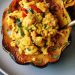 savory stuffed acorn squash with curried ground turkey on a gray plate with a blue background