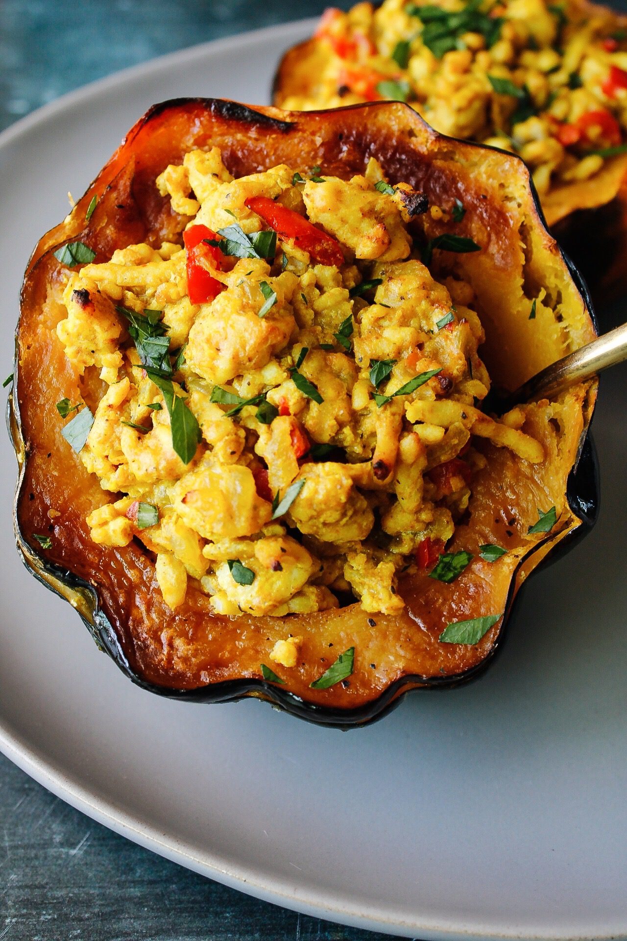savory stuffed acorn squash with curried ground turkey on a gray plate with a blue background