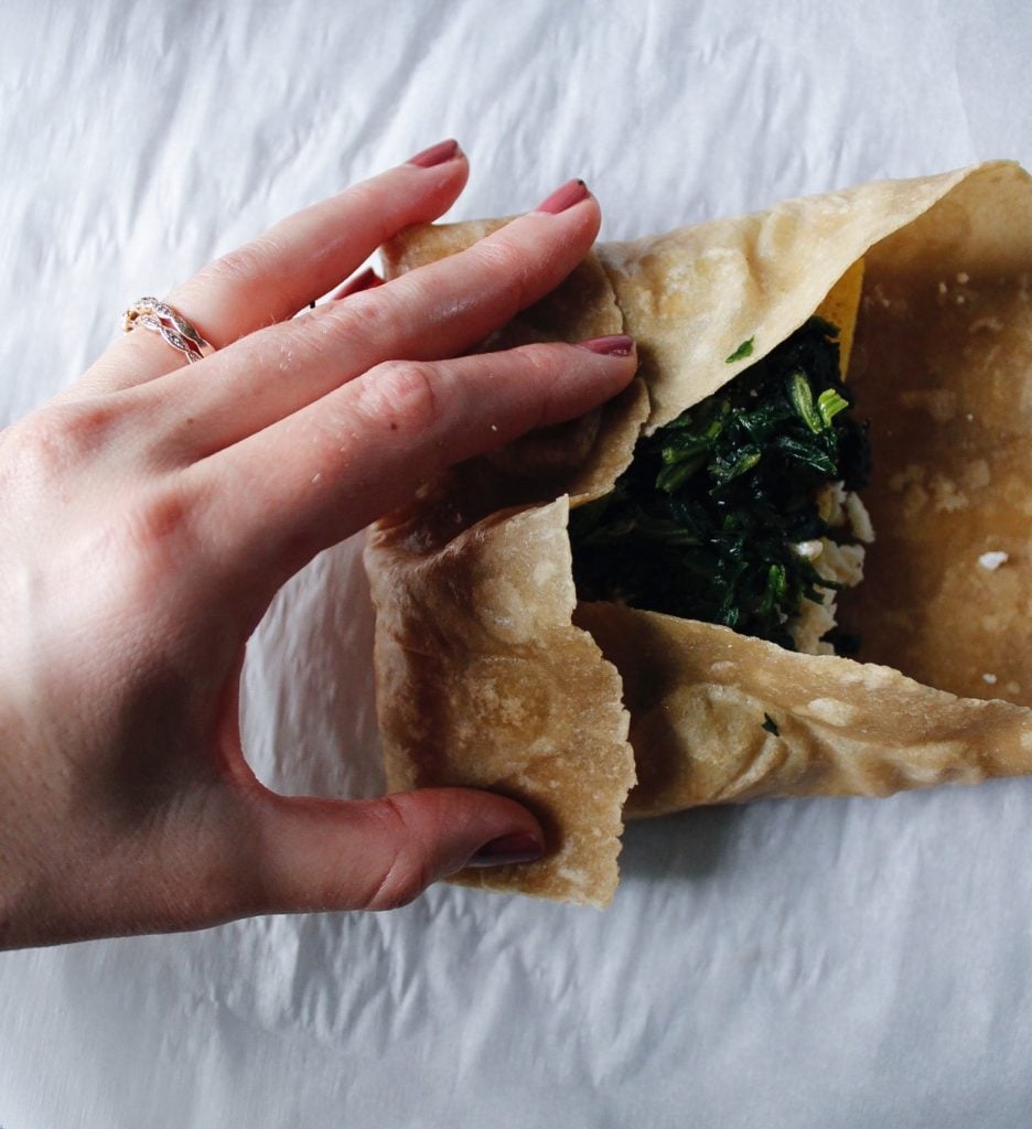 spinach feta wrap in the process of being tucked and folded