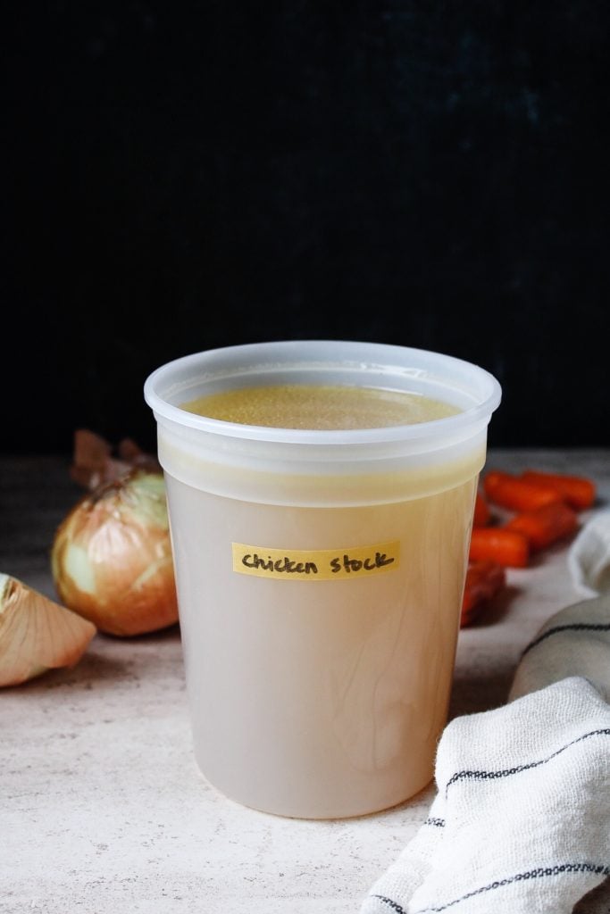 homemade chicken stock in a storage container, labeled with washi tape.