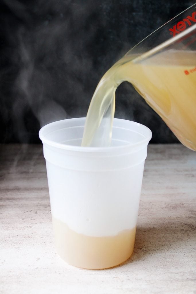 homemade chicken stock being poured into a plastic container