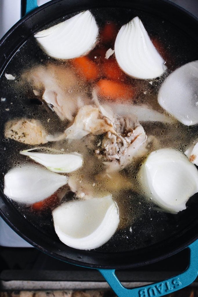 homemade chicken stock in the making. chicken carcass, onion, carrot and water in a dutch oven.