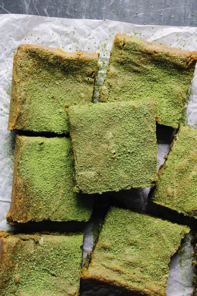 matcha brownies dusted with matcha green tea powder on parchment paper