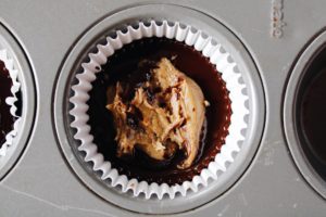 sunbutter added to melted dark chocolate in a cupcake liner