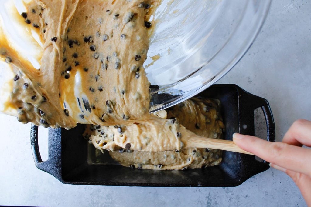 peanut butter bread batter being poured into a loaf pan for baking