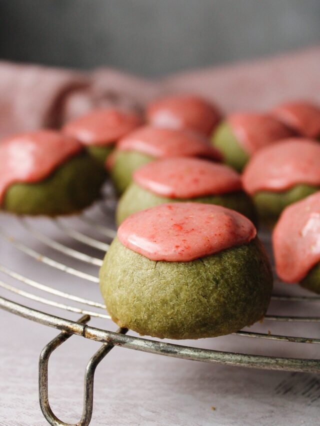 matcha shortbread cookies with strawberry icing on an antique cooling rack