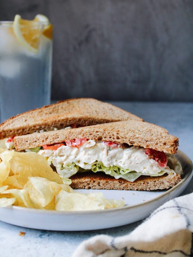 sideview of the best chicken salad sandwich on wheat bread with butter lettuce and tomatoes