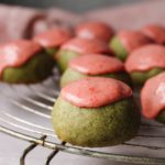 matcha shortbread cookies with strawberry icing on an antique cooling rack