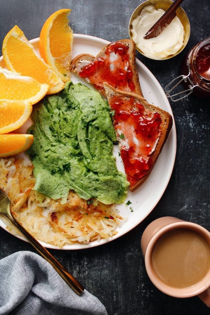 overhead shot of spinach eggs on a plated with fruit, toast and hashbrowns.