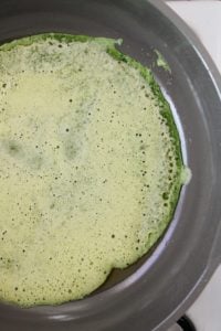 spinach eggs just poured into the pan, beginning to cook around the edges.