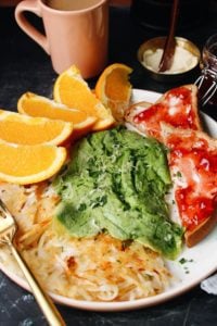 spinach eggs on a plated with hashbrowns, oranges and toast