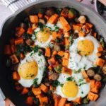 breakfast sweet potatoes in a skillet topped with eggs
