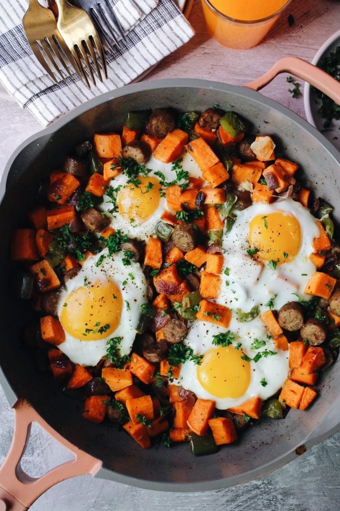 breakfast sweet potatoes in a skillet topped with eggs