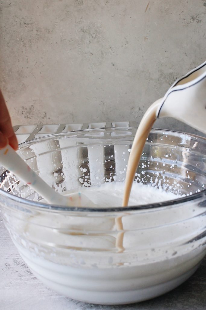 earl grey and sweetened condensed milk mixture being poured into whipped cream mixture
