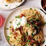 pasta with peas and prosciutto on beige plates with wine and extra toppings