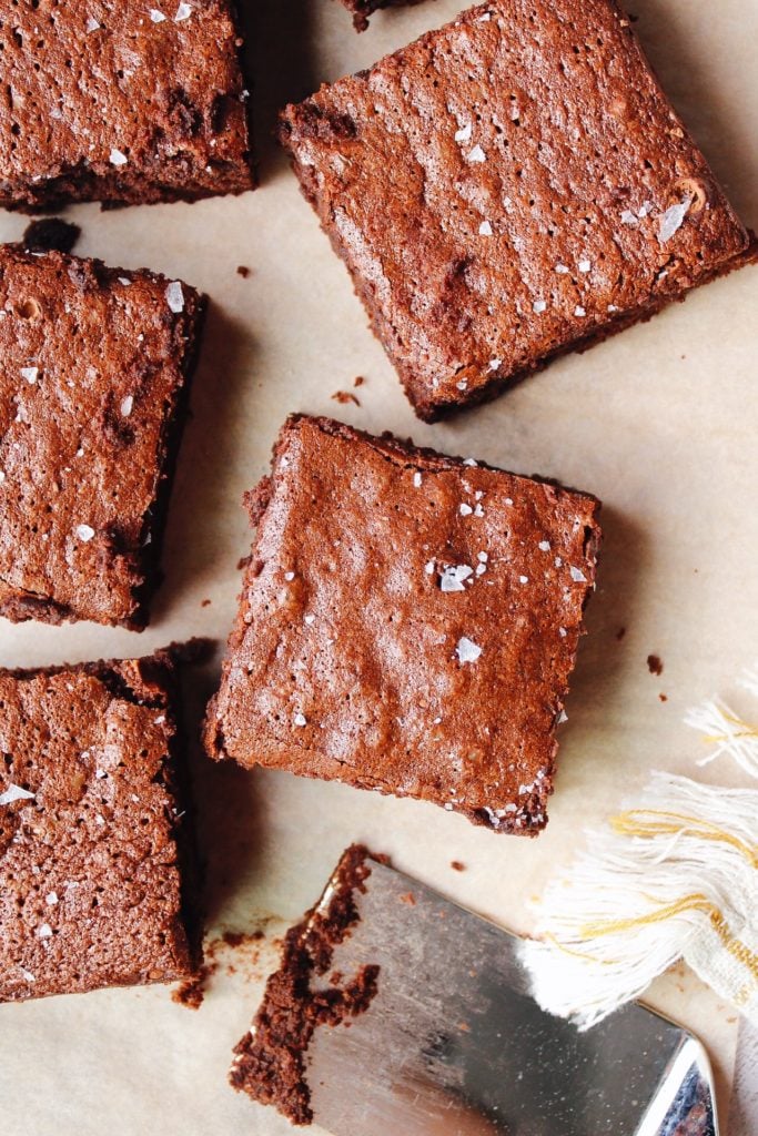 sourdough discard brownies arranged on parchment paper and topped with sea salt