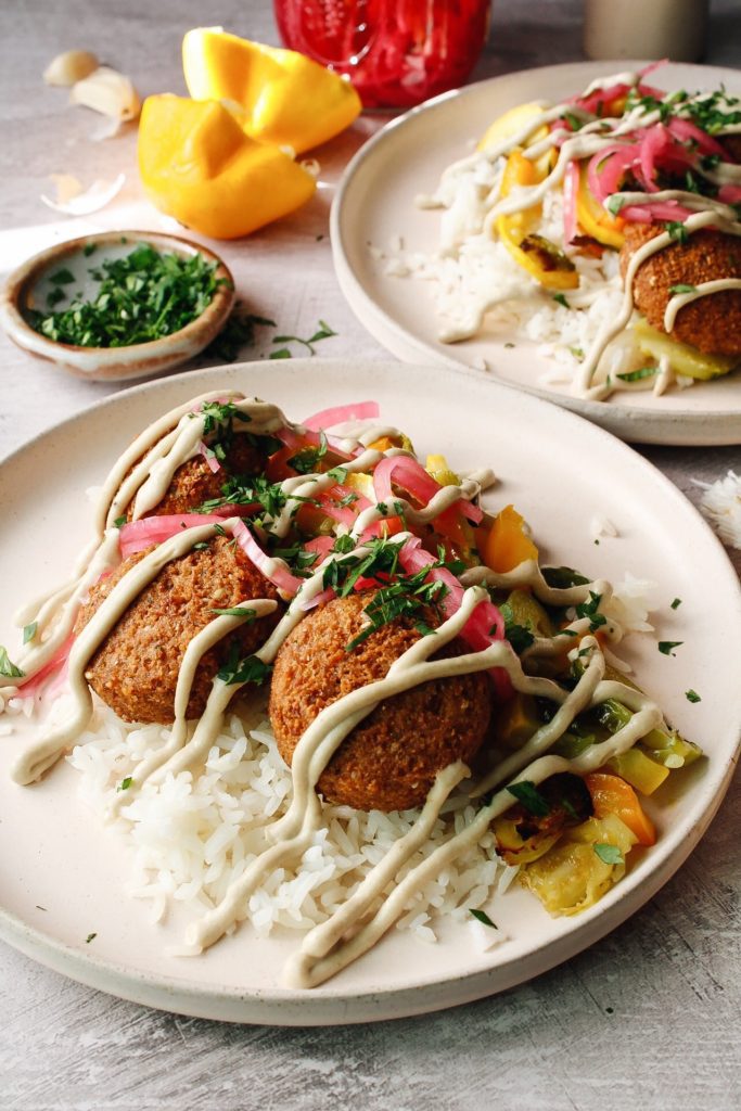 side view of trader joe's falafel on plates with veggies, rice and tahini sauce
