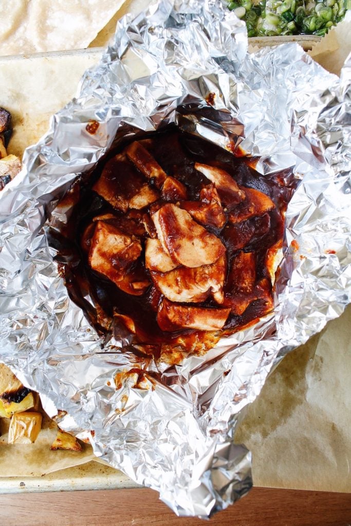 bbq chicken wrapped in a bundle of foil to reheat in the oven