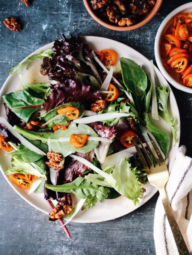 Roasted kumquat salad with candied pecans and cheese on a plate